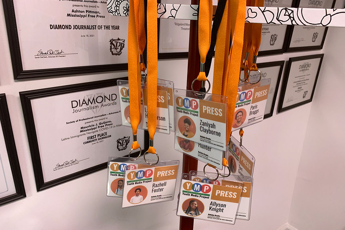 Multiple badges that read YMP Press at the top hang from bright orange lanyards