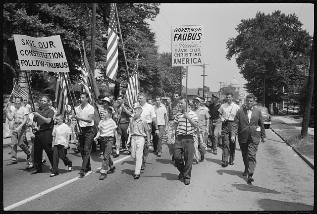 white men and boys march holding signs that say "Save our constitution - follow fabus" and "Governor Faubus Please Save Our Christian America"