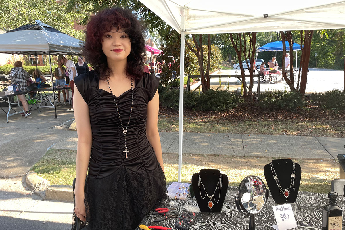 Tessa Luke stands beside her table of handmade necklaces