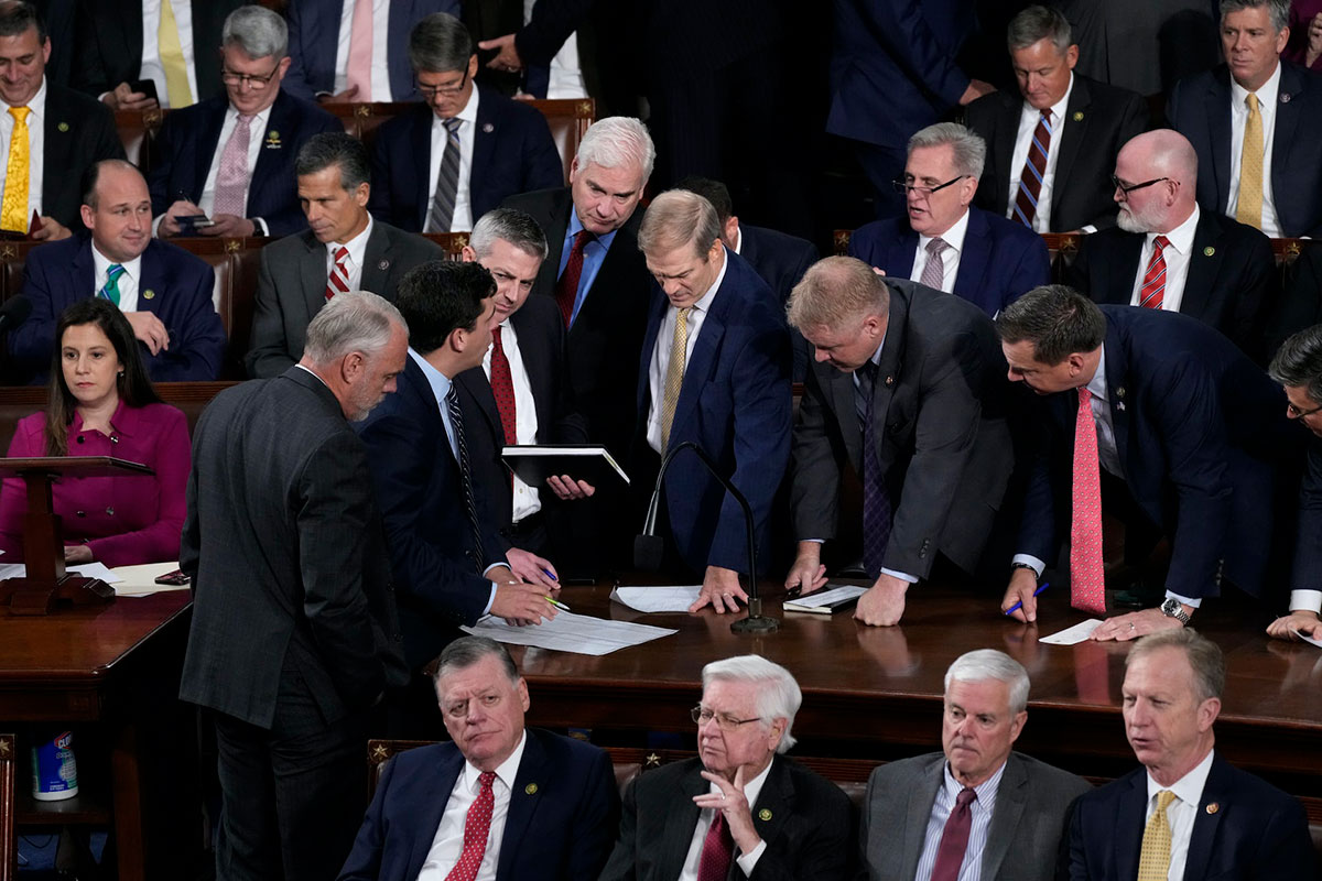 Jim Jordan is surrounded by several other members of Congress as they look on at a piece of paper