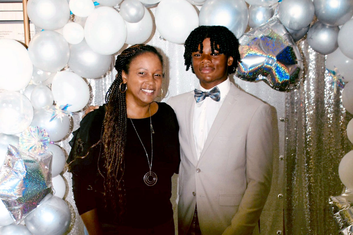 Tameka Tobias and her 14 year old son Dylan pose in front of white and silver balloons