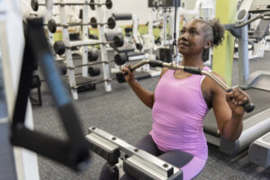 A woman in pink exercise gear uses gym equipment