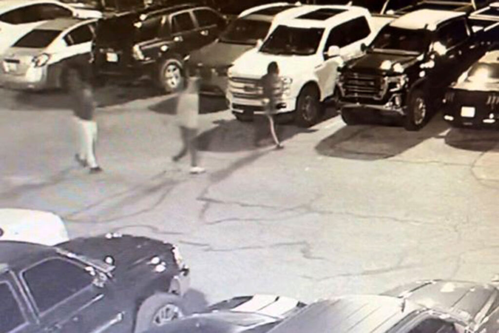 Security footage of three people walking through a parking lot