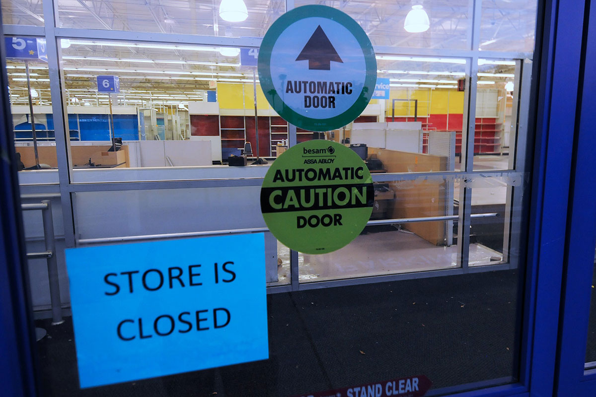 A STORE IS CLOSED sign is affixed to an automatic door at the entrance of a Toys R Us location