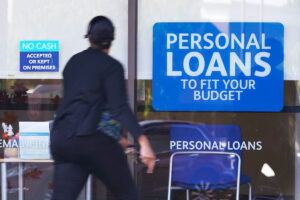 A person walking in front of a building with signs about Persona Loans all over the front (AI)