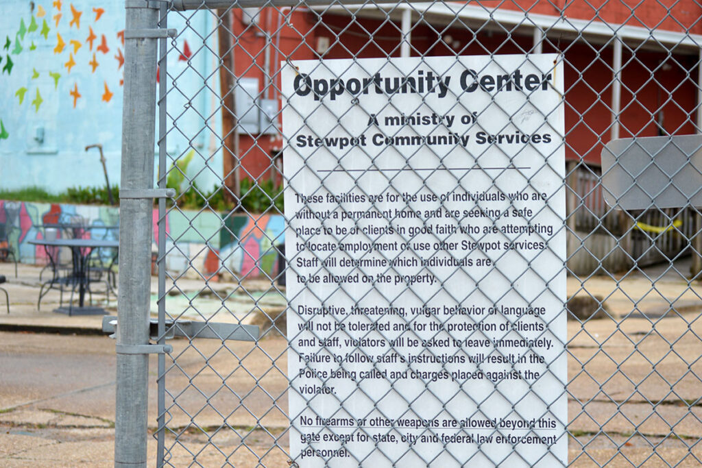 Exterior photo of the Stewpot Opportunity Center through the chain link fence