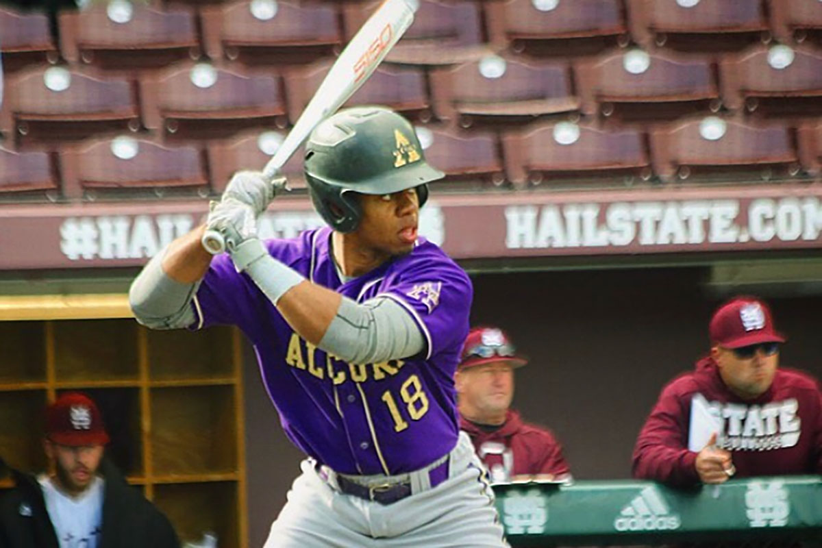 Brandon Rembert ready to swing a baseball bat while wearing a purple Alcorn #18 baseball uniform
