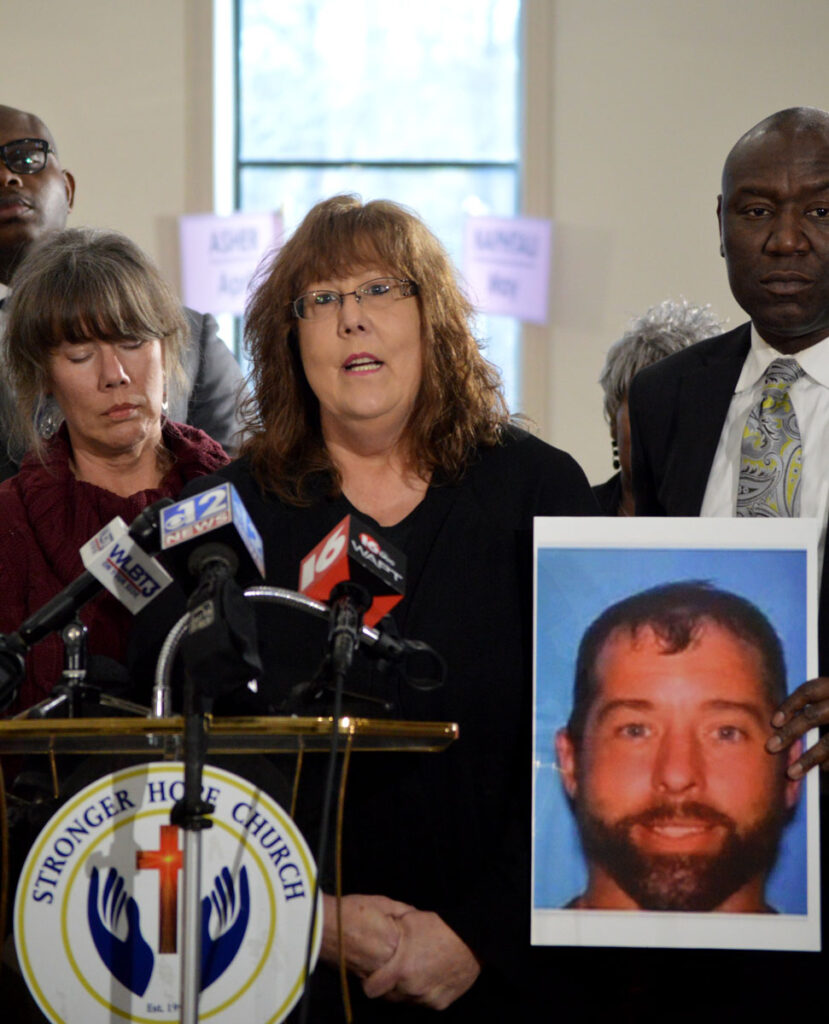 Gretchen Hankins speaks at a press conference while a man holds a large photo of her son to the right