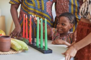 African little child burning candles for Kwanzaa holiday to celebrate with her family