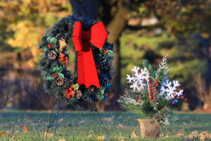 Two holiday themed funerary floral arrangements stand outside