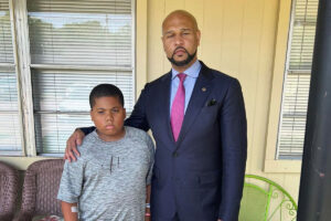 Attorney Carlos Moore (right) is pictured alongside 11-year-old Aderrien Murry on a porch outside