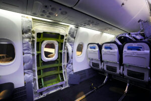 A row of seats are removed from the inside of ain airplane, and the emergency exit door is dismantled and exposed