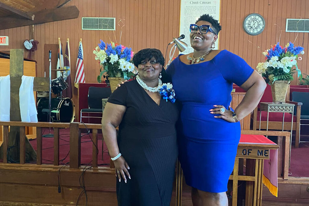 Two women in blue dresses pose inside a church