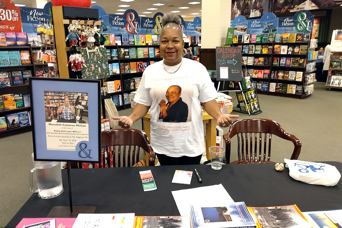 Meredith Coleman McGee standing at her book signing table inside a bookstore