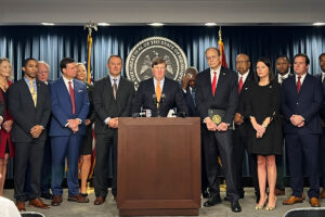 Lawmakers stand behind a podium. The great seal of the state of Mississippi is behind them.