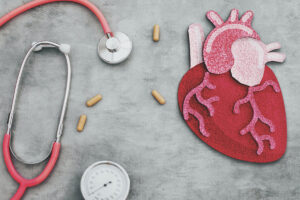 An artful layout of a stethoscope and a heart with four pills scattered between them