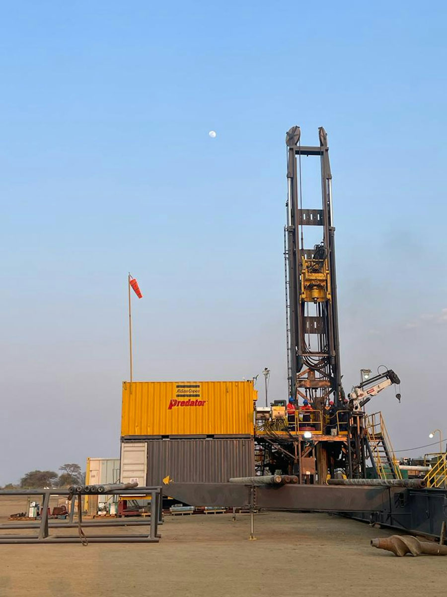 A tall steel drilling rig and a large yellow container, with a red flag on top of the container. (helium)