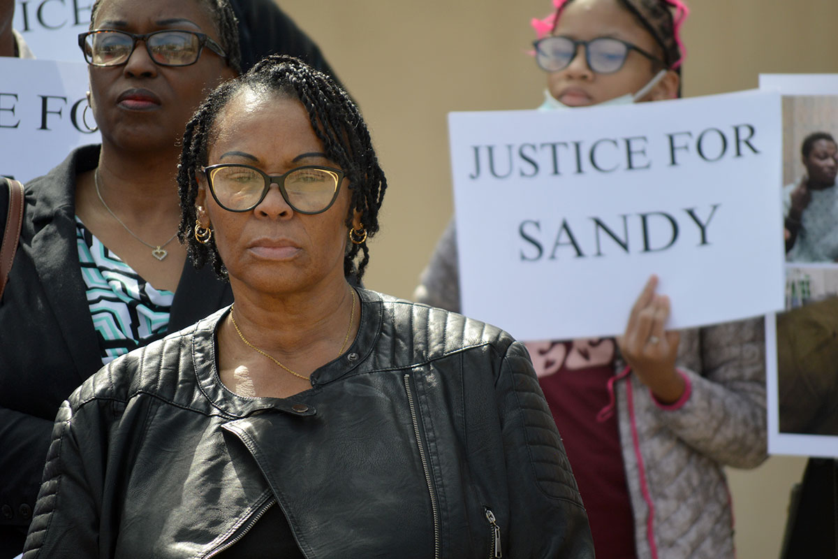 Susie Balfour, pictured outside the Thad Cochran United States Courthouse as several people hold signs calling for justice behind her