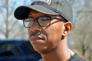 Headshot of Mac Epps seen wearing a black Tougaloo cap and black glasses