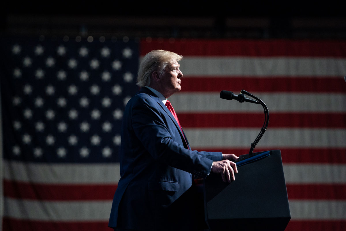 President Donald Trump speaks at a podium with the US flag behind him