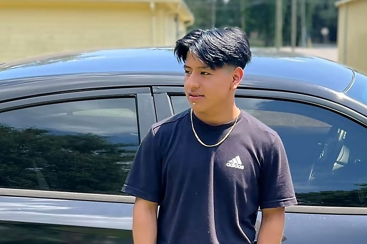 Duvan Tomas Pérez stands outside in front of a black car