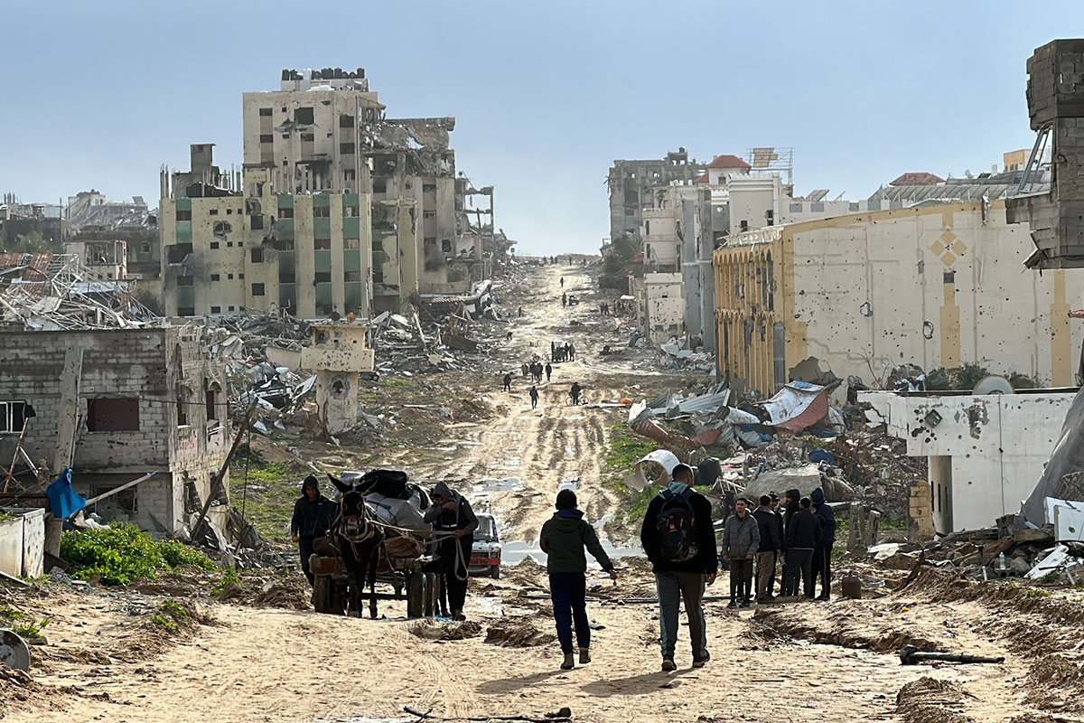 People are seen walking down a war torn road inside a town area of Gaza
