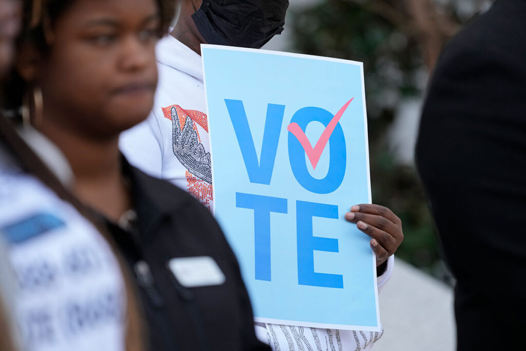 A member of a voting rights group holds a "vote" sign