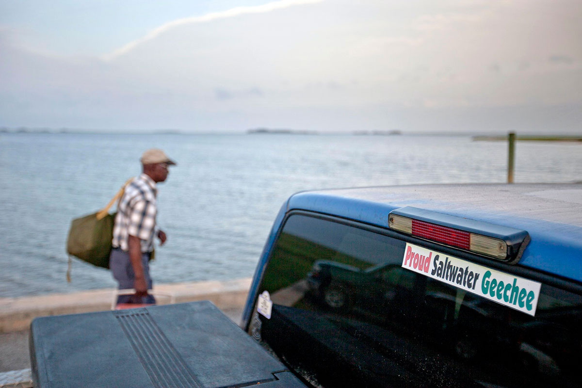 A sticker celebrating the Geechee heritage is seen on a pickup truck as passengers board a ferry