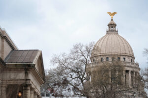 A view of the top of the Mississippi state capitol building. A golden eagle sits, wings spread, on top of the dome roof