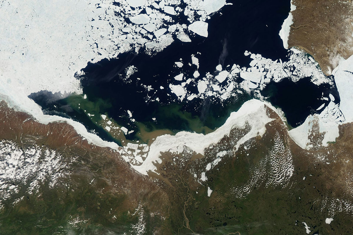 A satellite view of the Arctic coast showing a river and sea ice breaking up