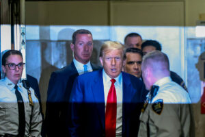 Former President Donald Trump arrives for the start of a court hearing, surrounded by security.