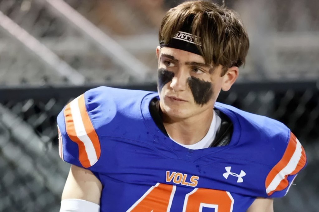 A teen boy in a blue and orange football uniform and black tar smeared on his cheeks