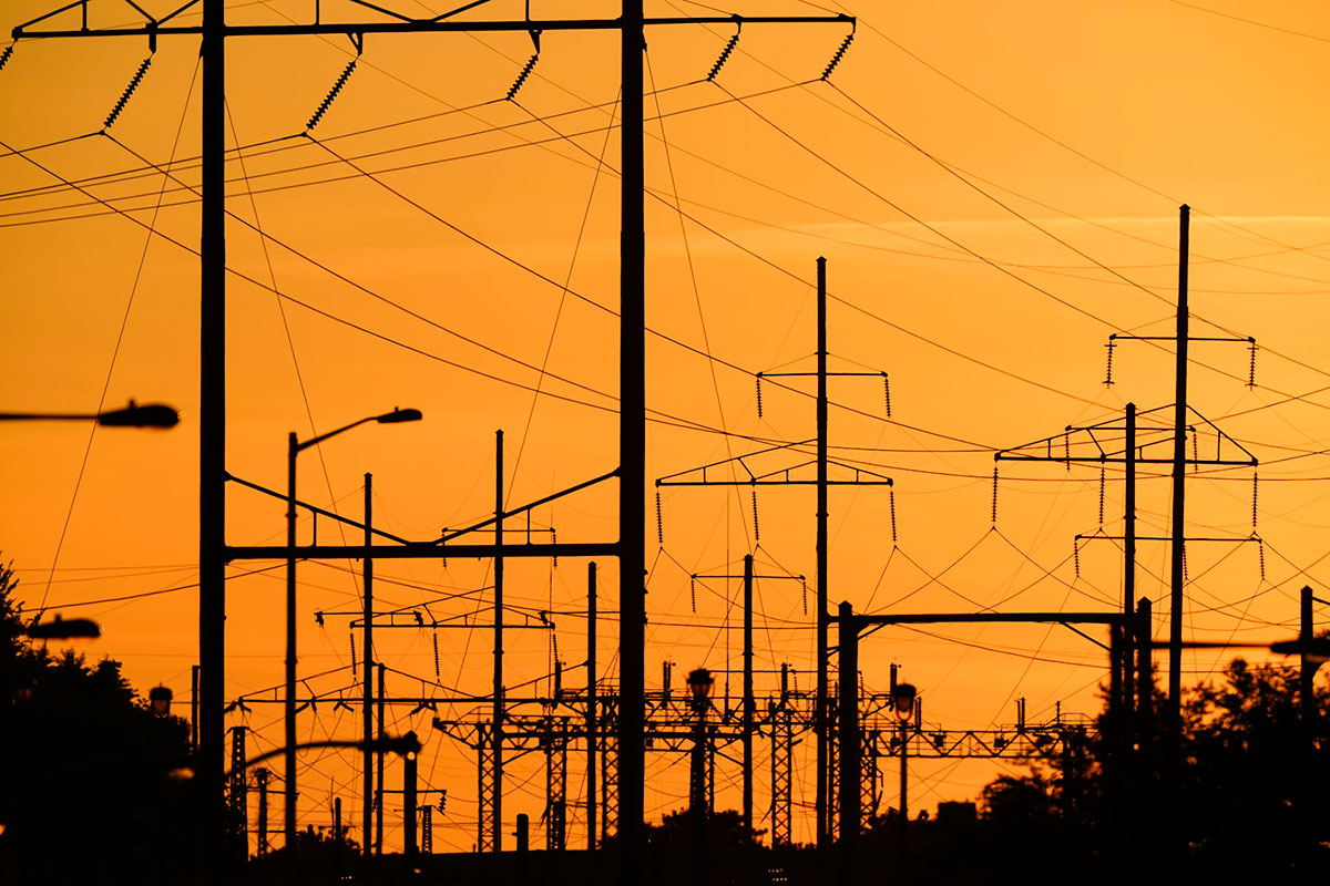 Electrical towers and power lines shown against a sunset