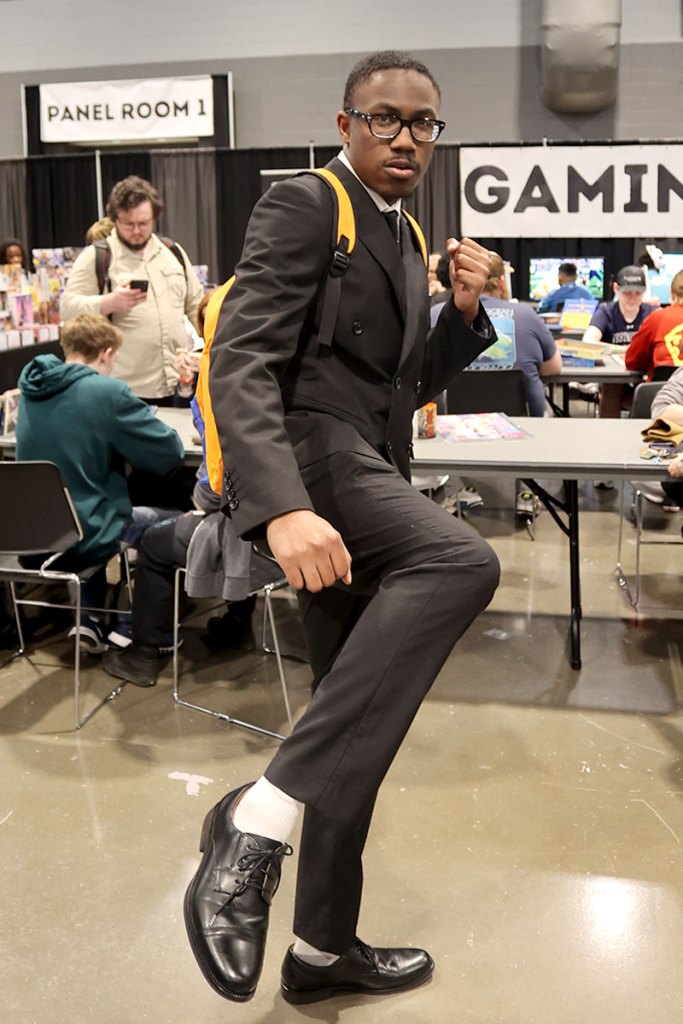A man takes a fighting pose, one leg in the air and one fist raised