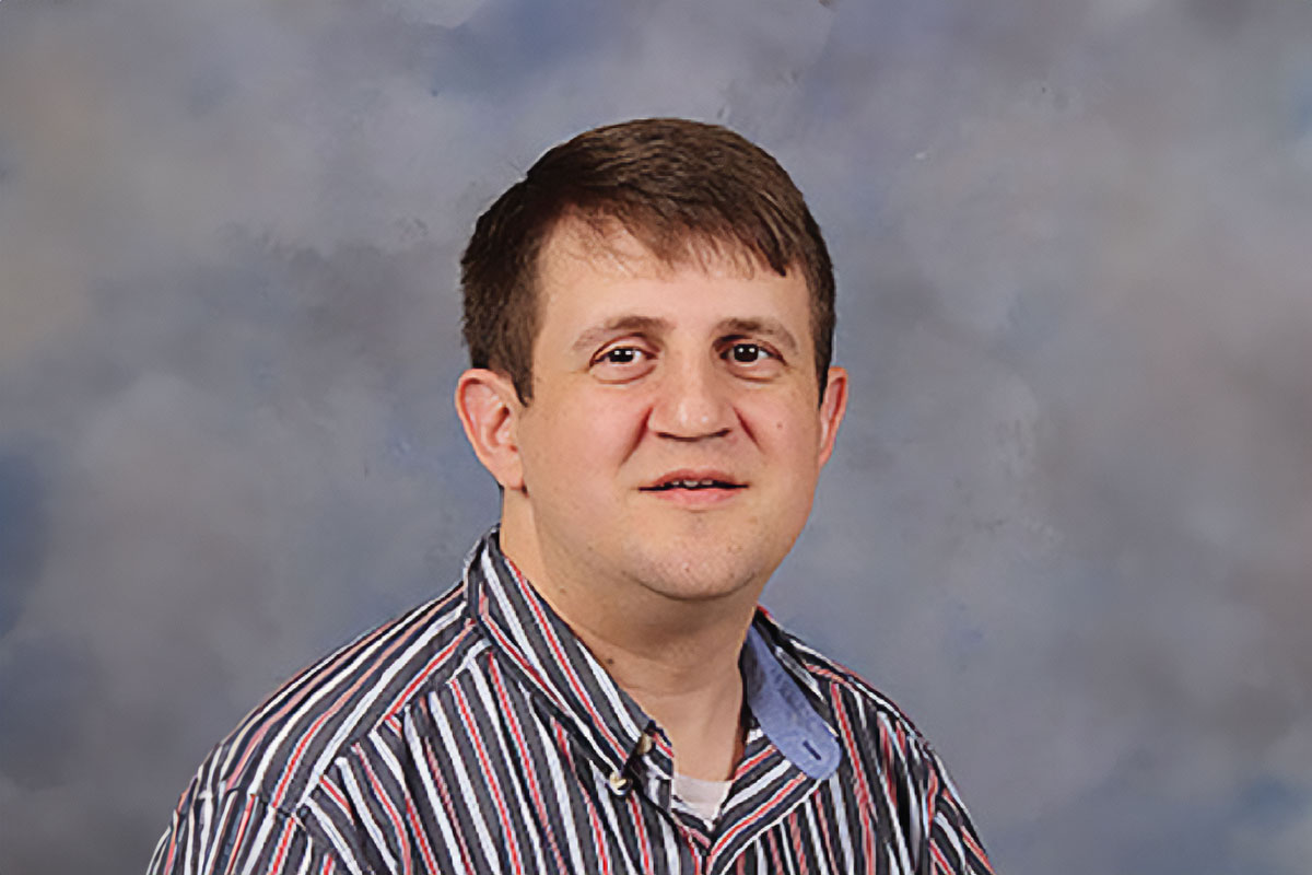 Greg Pigott headshot wearing a striped shirt