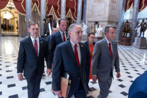 Five state representatives walk through the Senate hallways, the lead person is bearing a few paper files