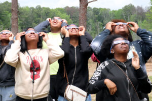 Teens look up at the sky while wearing solar glasses