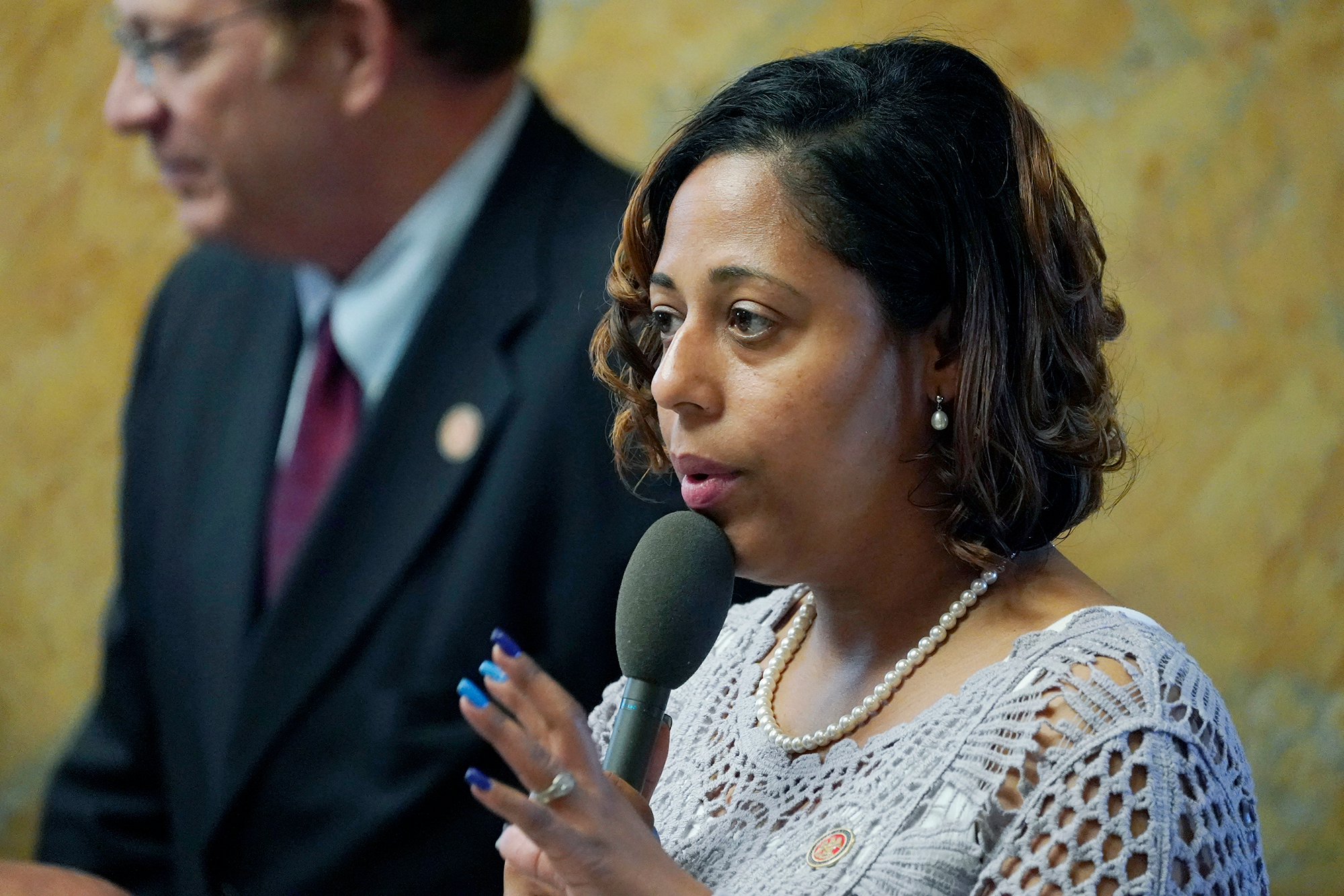 A woman holding a mic asks a a question in a capitol debate