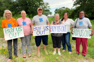 Six people hold signs that read "Buy Us Out"