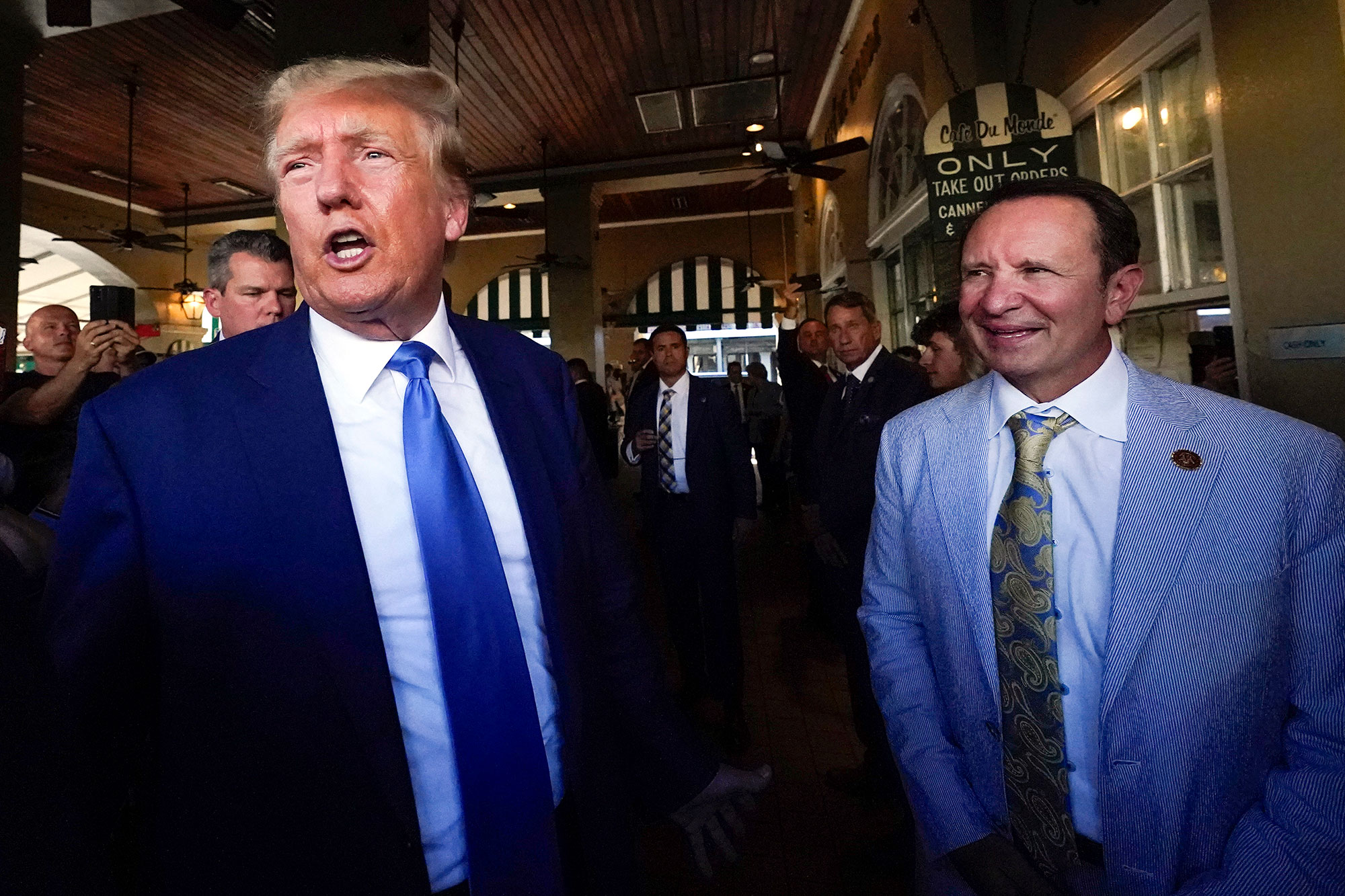 Two men in suits walk through a restaurant patio