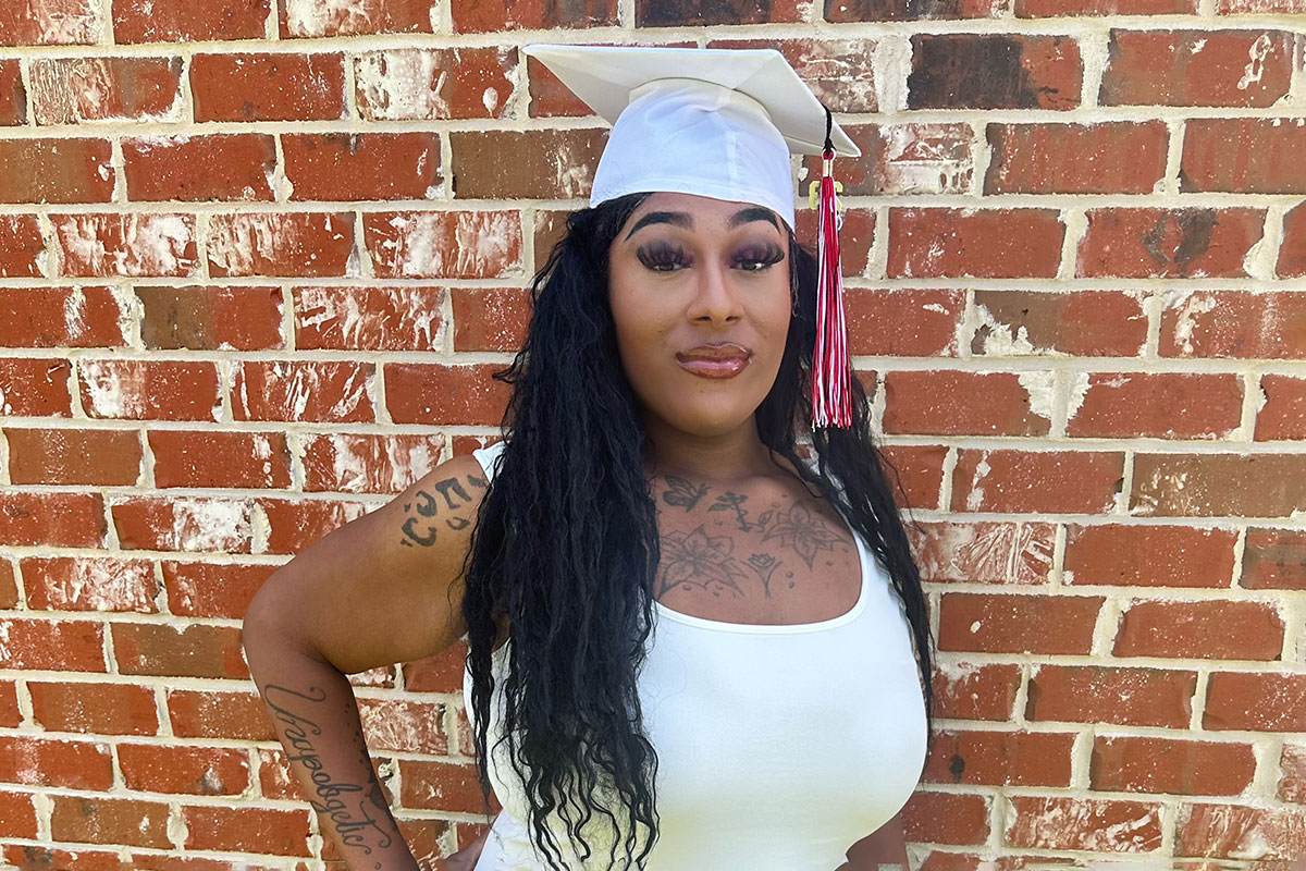 L.B. dressed in white and wearing a white graduation cap