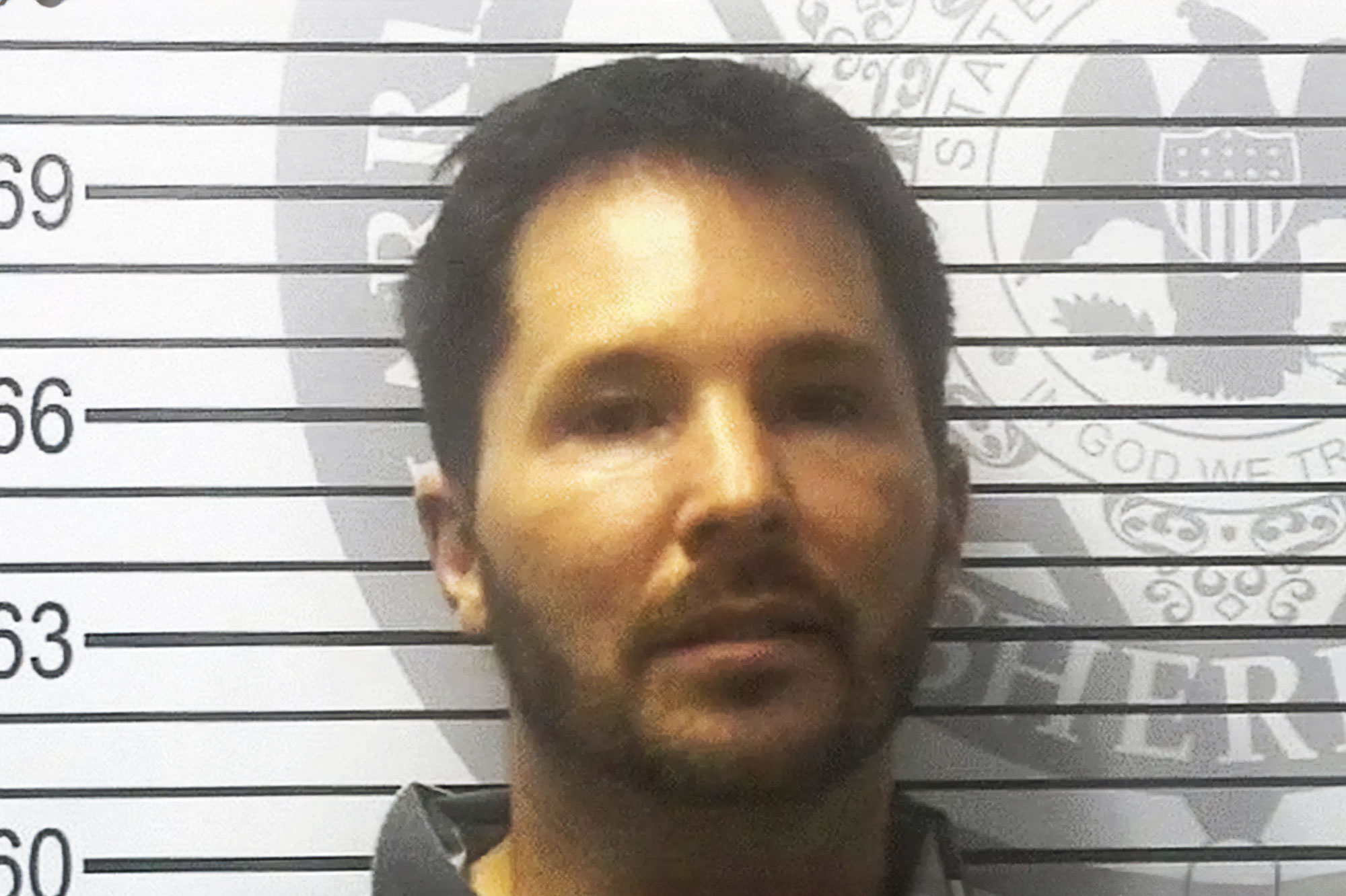 A mugshot of a man against a wal with height line marks