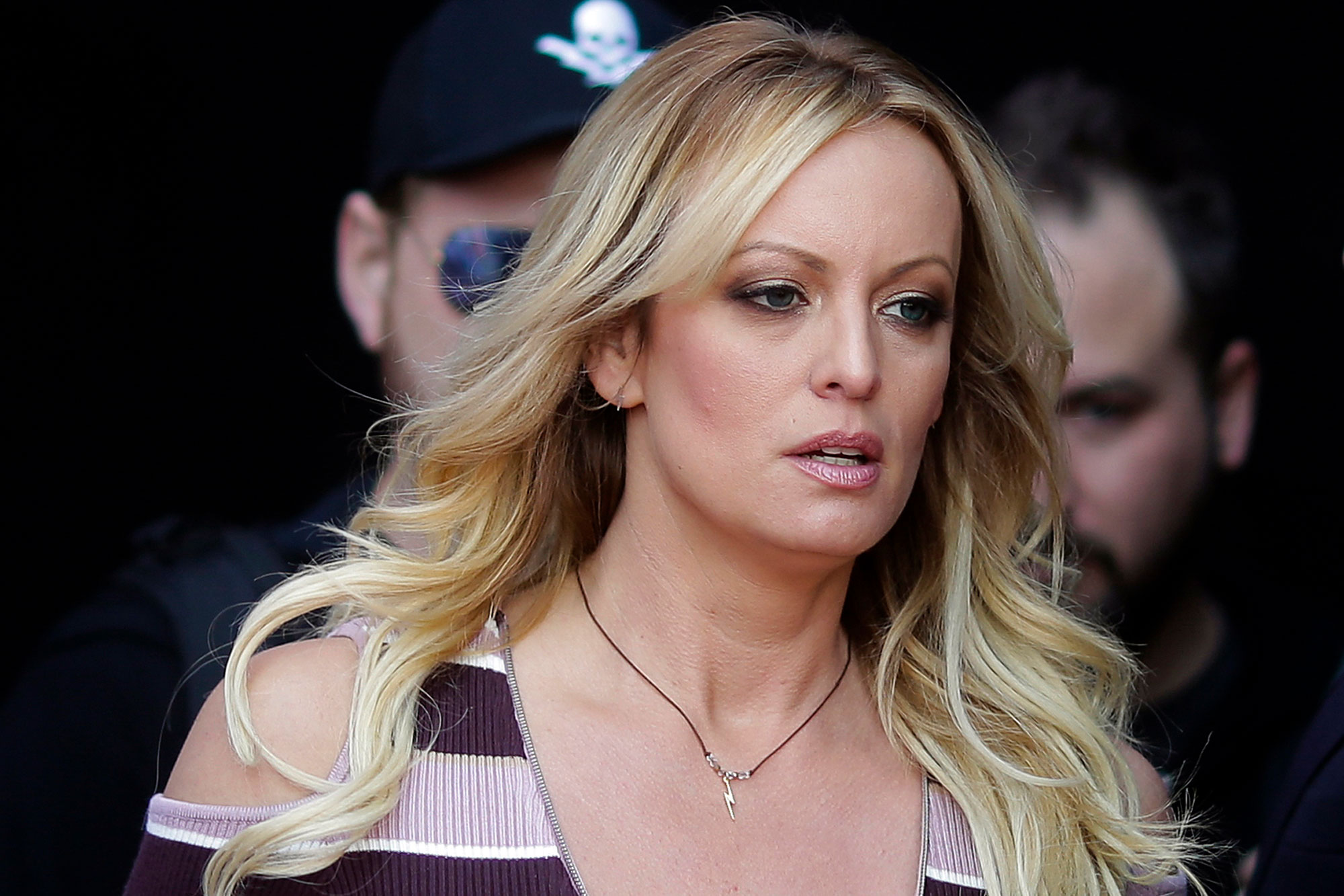 A blond woman looks off to the right as she walks int a room