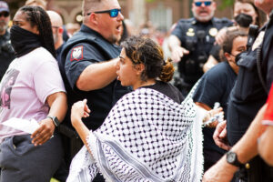 a pro-Palestine woman protestor is surrounded by UM campus police
