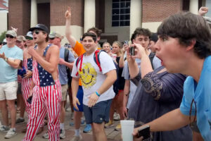 A crowd of white male ole miss students laughing and making obscene jeers