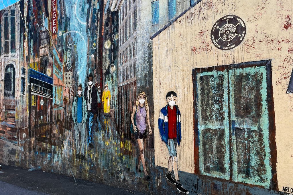 A mural of people walking through a downtown street while all wearing medical face masks.