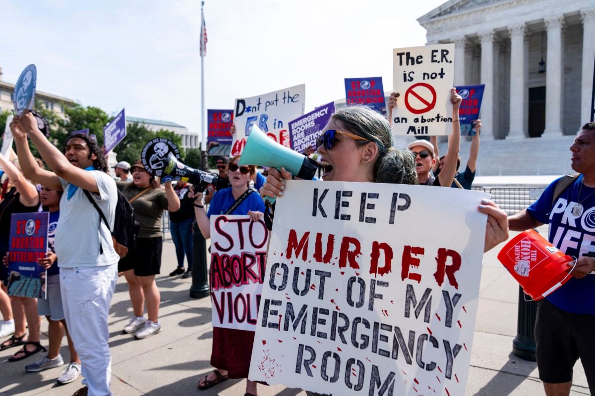Anti-abortion demonstrators protest outside the Supreme Court with signs that say things like "Keep murder out of my emergency room"