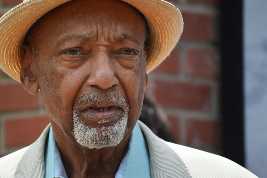A closeup of a man in a hat standing outside