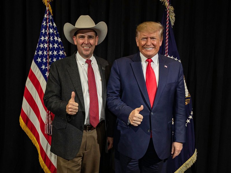 Two men stand side by side and do a thumbs up pose.