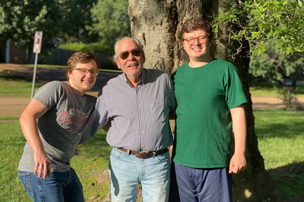 A man and his two sons stand together outside
